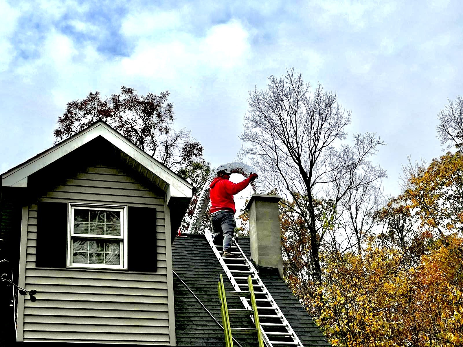 Technician relining a chimney on a roof with a flexible liner.